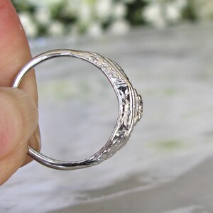 May include: A silver ring with an intricate floral design and a small diamond in the center.