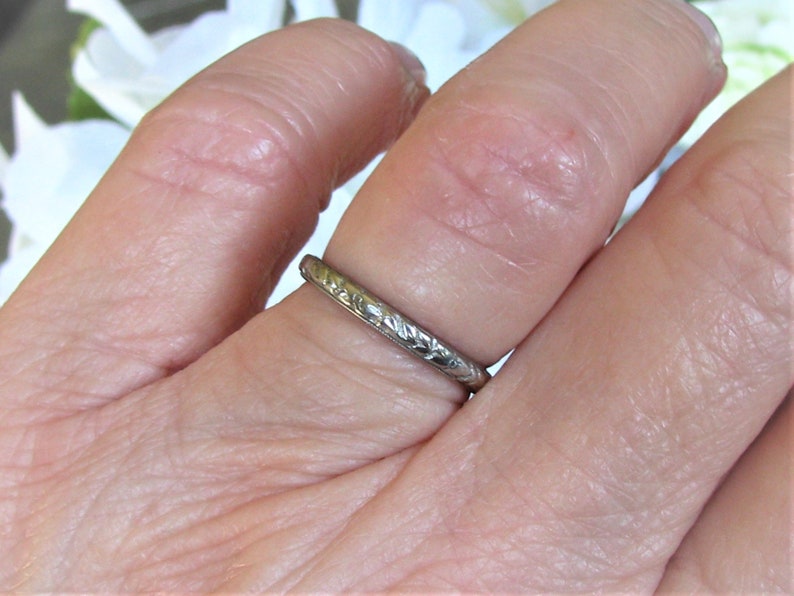 Puede incluir: Una fina banda de plata con un delicado dise&ntilde;o floral. El anillo se lleva en un dedo.