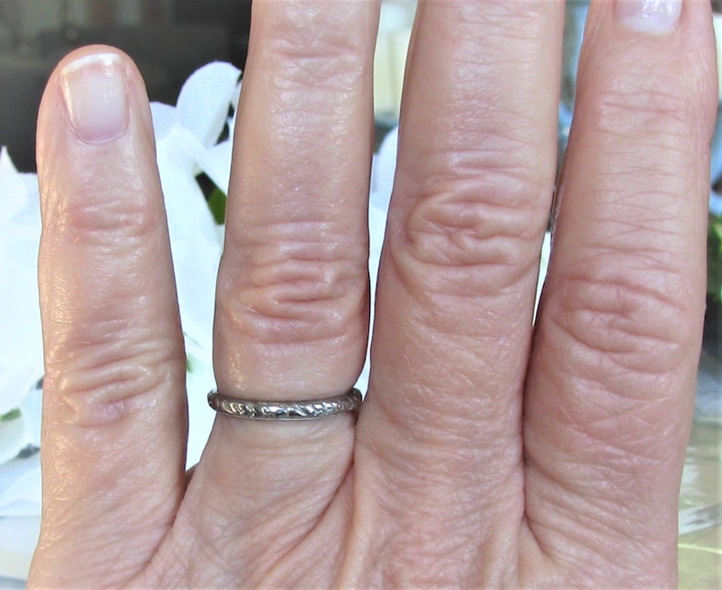 Puede incluir: Un anillo de banda de plata con un dise&ntilde;o texturizado. El anillo se lleva en un dedo.