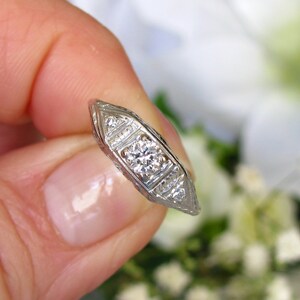 May include: A silver engagement ring with a central diamond and smaller diamonds set in a delicate, intricate design.