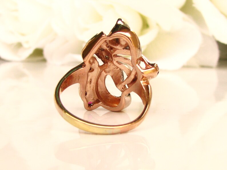 May include: A rose gold ring with a floral design. The ring is set with clear and pink stones.