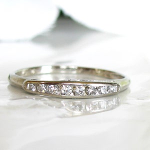 May include: A delicate silver band with a row of small, clear diamonds set in a channel setting.