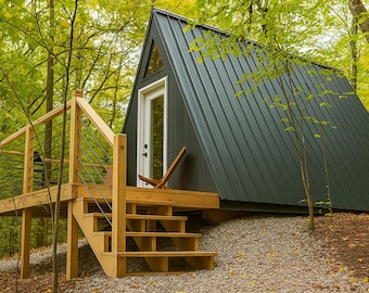 May include: A-frame cabin with a dark gray metal roof and white door, nestled in a forest. The cabin has a wooden deck and stairs with a simple railing. A wooden chair sits on the deck. The surrounding trees have green and yellow leaves.