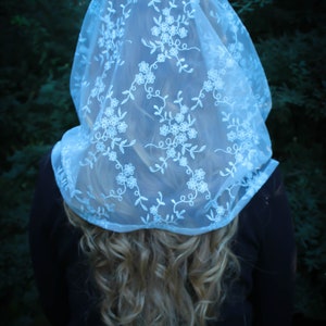 May include: A white lace veil with floral embroidery. The veil is sheer and delicate, with a soft, flowing texture.