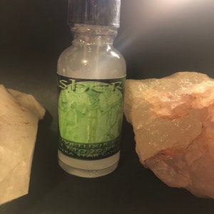 May include: A clear glass bottle with a black cap and a green label that says "Elixir 1 to 20 drops", "Terra Star Gods", and "As Above, So Below".