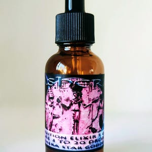 May include: An amber glass dropper bottle with a black cap and a rectangular label. The label features a pink graphic of an Egyptian figure and text that reads "STARDUST" at the top and "NUTRITION ELIXIR" with "USE 3 TO 20 DROPS" below.