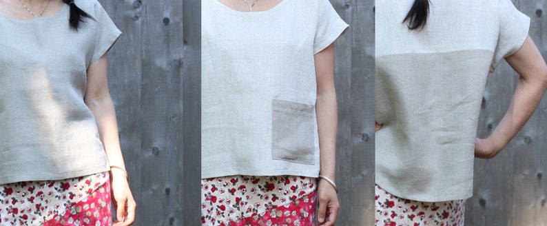 May include: A light beige linen top with short sleeves and a round neckline. The top features a patch pocket on the front and a contrasting panel across the back. The fabric has a slightly textured appearance. The top is paired with a floral print skirt.
