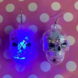Pendientes de calavera iluminados y divertidos con cierre de gancho o clip en dorado o plateado.