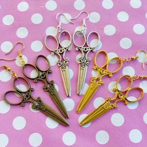 Grandes pendientes de tijera ornamentados en oro, plata o bronce con cierre de gancho o clip.