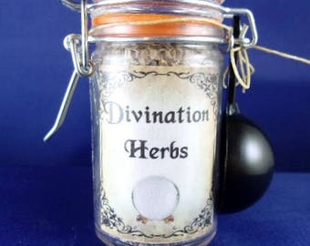 May include: A glass jar with a metal clasp and an orange seal, labelled "Divination Herbs" with a crystal ball graphic. A black scoop is attached. The jar sits on a blue surface. Measurements are in cm.