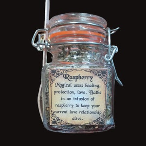 May include: A glass jar with a metal clasp lid filled with dried herbs. The label reads "Raspberry Magical uses: healing, protection, love. Bathe in an infusion of raspberry to keep your current love relationship alive."