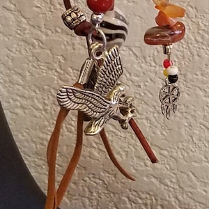May include: A brown leather keychain with a silver eagle charm, a silver eagle pendant, and a variety of beads in red, orange, yellow, white, and black.
