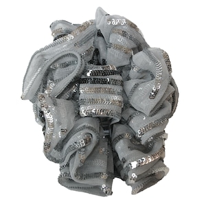 May include: A silver and gray sequined hair scrunchie with a ruffled design.
