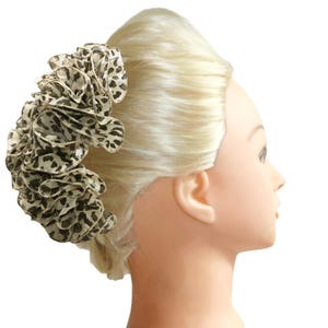 May include: A brown and white leopard print hair scrunchie with a ruffled design.