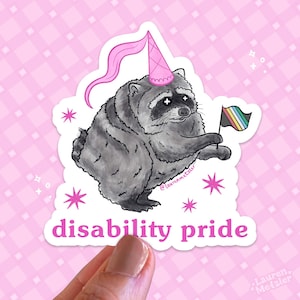 May include: A die-cut sticker featuring a grey raccoon wearing a pink party hat with a long streamer. The raccoon holds a small flag with black, grey, white, blue, and yellow stripes. The text disability pride is printed in pink below the raccoon.