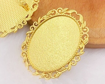 May include: Two gold-toned oval-shaped metal blanks with ornate edges. The blanks are designed for use with resin or other materials to create custom jewelry.