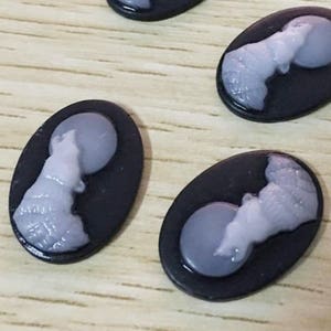 Può includere: Sei cabochon ovali neri con disegni di lupo bianco che ulula alla luna.