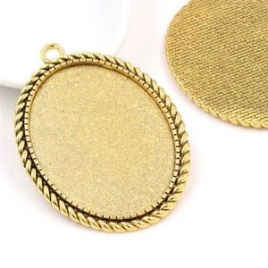Könnte beinhalten: Zwei goldene, ovale Metall-Anhänger-Tabletts mit einem seilartigen Rand. Ein Tablett hat eine glatte Oberfläche, das andere eine strukturierte Oberfläche.