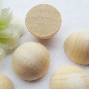 May include: Five unfinished wooden half-sphere ornaments. The ornaments are light brown and have a smooth, slightly textured surface.