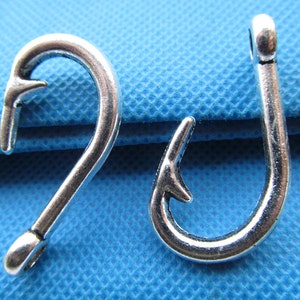 Op de afbeelding: Twee zilverkleurige metalen vishaken. De haken zijn ongeveer 5 cm lang en hebben een scherpe punt.