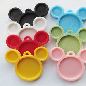 Puede incluir: Siete dijes de plástico con forma de Mickey Mouse en diferentes colores: negro, blanco, rojo, amarillo, azul claro, verde y rosa. Cada dije tiene un centro redondo y dos círculos más pequeños para las orejas.