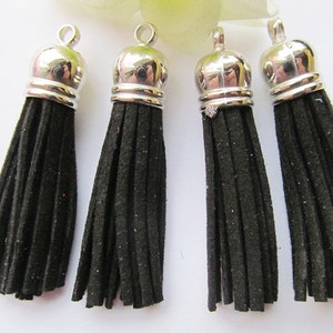 May include: Four black suede tassels with silver metal tops. The tassels are approximately 2 inches long.