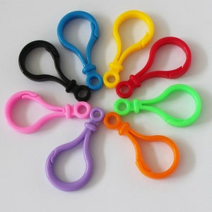 Puede incluir: Surtido de ocho llaveros de plástico de colores con un gancho y un lazo. Los llaveros son de color negro, azul, rosa, morado, verde, naranja, rojo y amarillo.