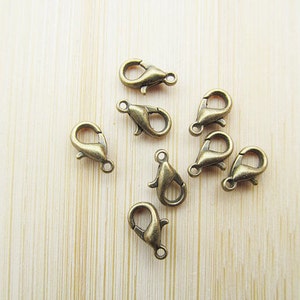 May include: Eight antique gold-toned lobster clasps, a type of fastener used in jewellery making.