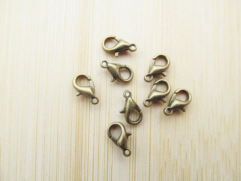 May include: Eight antique gold-toned lobster clasps, a type of fastener used in jewellery making.