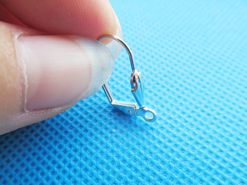 May include: Silver earring hook with a small loop at the end. The hook is made of metal and has a shiny finish.