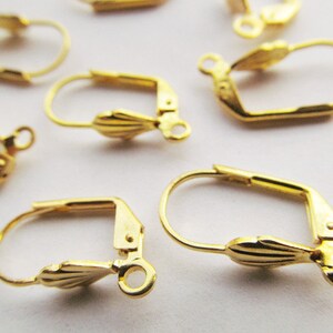 May include: Gold-toned earring hooks with a decorative scallop design. The hooks are made of metal and have a spring-loaded closure.