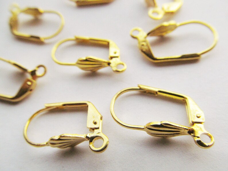 May include: Gold-toned earring hooks with a decorative scallop design. The hooks are made of metal and have a spring-loaded closure.