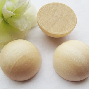 May include: Three round wooden cabochons, each with a smooth, slightly textured surface. The cabochons are a light beige color.