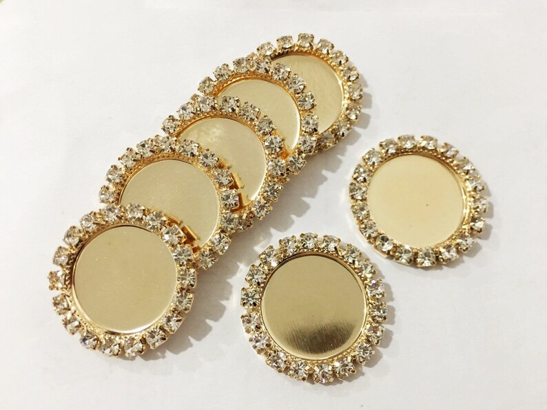 May include: Six gold-toned round metal trays with clear rhinestone borders. The trays are perfect for crafting and jewelry making.