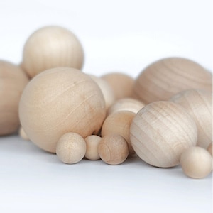 Op de afbeelding: Een verzameling houten bollen van verschillende groottes, variërend van klein tot groot, in een natuurlijke houtkleur. De bollen zijn in een cluster gerangschikt, waardoor een visueel aantrekkelijk en textuurrijk display ontstaat.