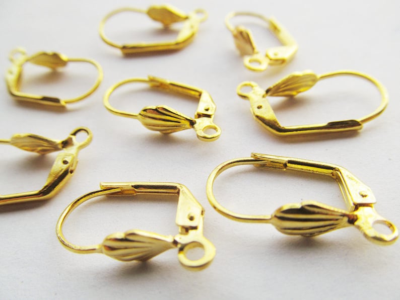 May include: Gold-toned earring hooks with a scalloped design. The hooks are made of metal and have a spring-loaded closure.