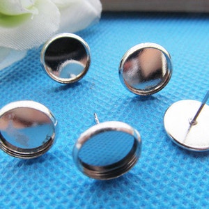 Puede incluir: Cuatro engastes para pendientes de color plateado con una base redonda y plana y una peque&ntilde;a c&uacute;pula redonda de vidrio transparente. Los engastes est&aacute;n dise&ntilde;ados para sujetar una peque&ntilde;a pieza de joyer&iacute;a, como una piedra preciosa o un amuleto.