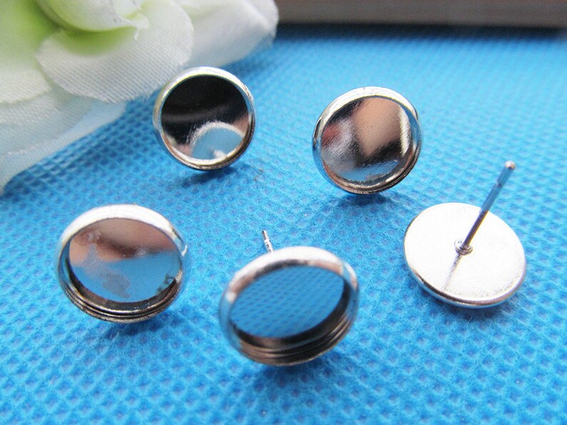 Puede incluir: Cuatro engastes para pendientes de color plateado con una base redonda y plana y una peque&ntilde;a c&uacute;pula redonda de vidrio transparente. Los engastes est&aacute;n dise&ntilde;ados para sujetar una peque&ntilde;a pieza de joyer&iacute;a, como una piedra preciosa o un amuleto.