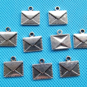May include: Ten silver-toned metal envelope charms with a loop for hanging. The charms are about 1 inch in size and have a detailed design.