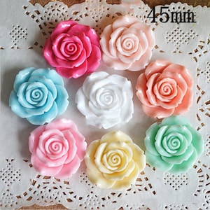 Puede incluir: Surtido de 7 cabujones de resina en forma de rosa de colores, cada uno con un diámetro de 45 mm. Las rosas son en tonos de rosa, azul, blanco, melocotón y verde.