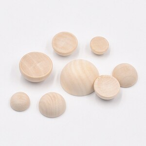 May include: Assortment of unfinished wooden half spheres and bowls in various sizes. The wood is a light natural color.