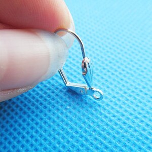 Peut inclure: Crochet d'oreille en argent avec une boucle à l'extrémité. Le crochet est ouvert et prêt à être attaché à une boucle d'oreille.