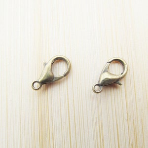 May include: Two gold-toned metal lobster claw clasps, commonly used for jewellery making.