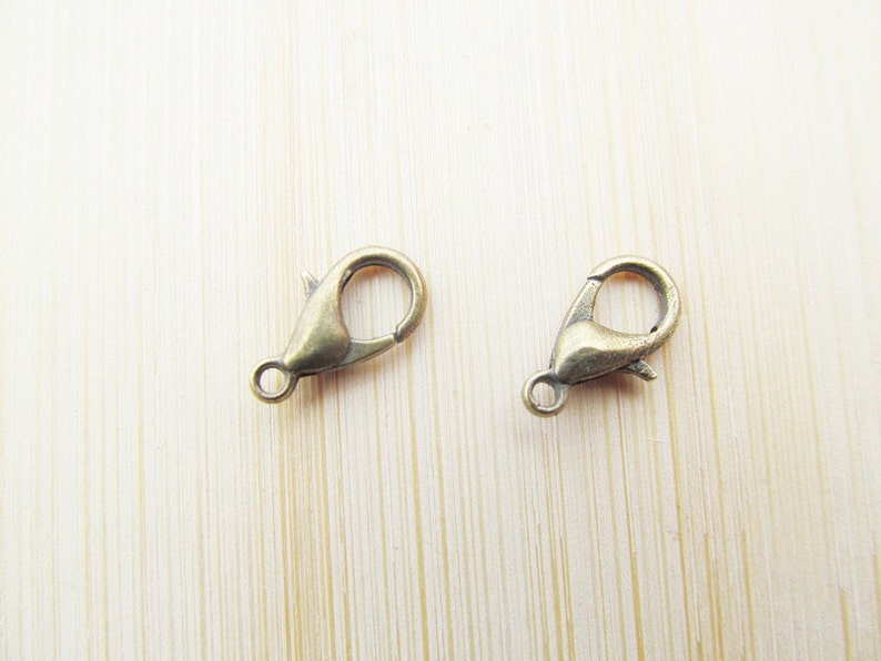 May include: Two gold-toned metal lobster claw clasps, commonly used for jewellery making.