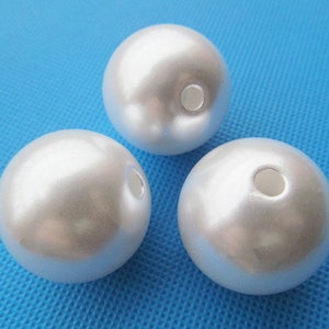 May include: Three white pearl-like round beads with a hole in the center. The beads are smooth and shiny.
