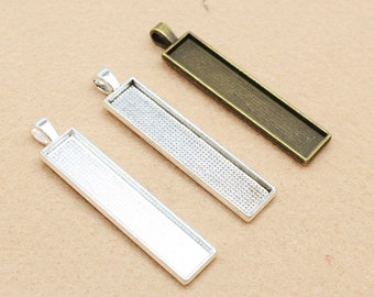 May include: Three rectangular pendant trays with a silver, antique silver, and gold finish. The trays are designed to hold small items like photos, charms, or other decorative elements.