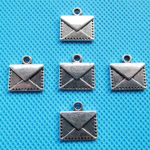 May include: Five silver-toned metal charms shaped like envelopes. Each charm has a loop at the top for attaching to a necklace, bracelet, or other jewelry.