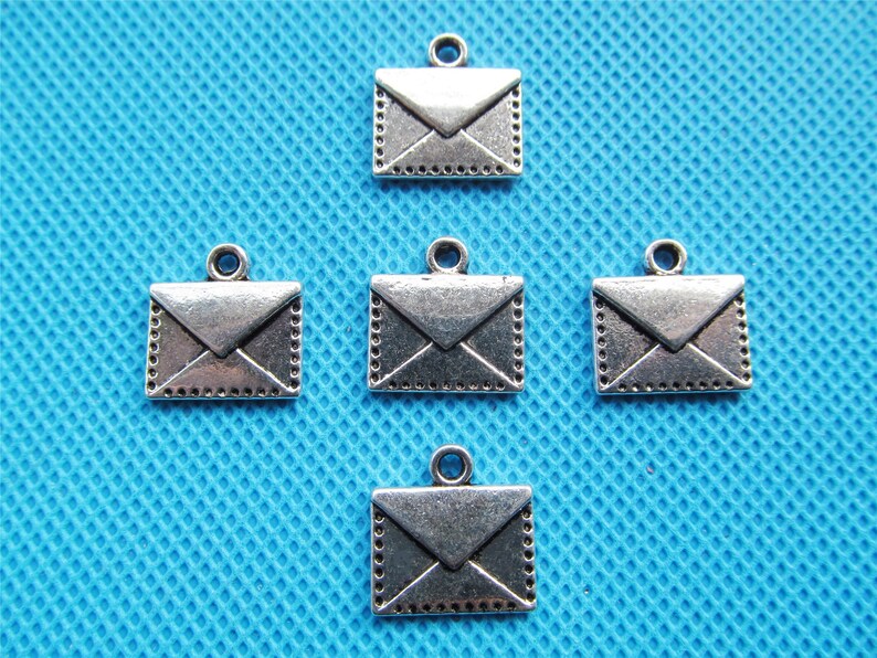 May include: Five silver-toned metal charms shaped like envelopes. Each charm has a loop at the top for attaching to a necklace, bracelet, or other jewelry.