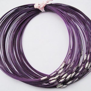 Puede incluir: Un mont&oacute;n de collares de alambre morado con cierres plateados. Los collares son todos de la misma longitud y est&aacute;n dispuestos en c&iacute;rculo.