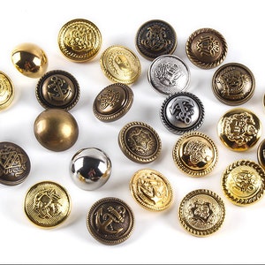 May include: Assortment of decorative metal buttons in various colors and designs, including gold, silver, and bronze. Some buttons feature anchors, crests, and other intricate details.